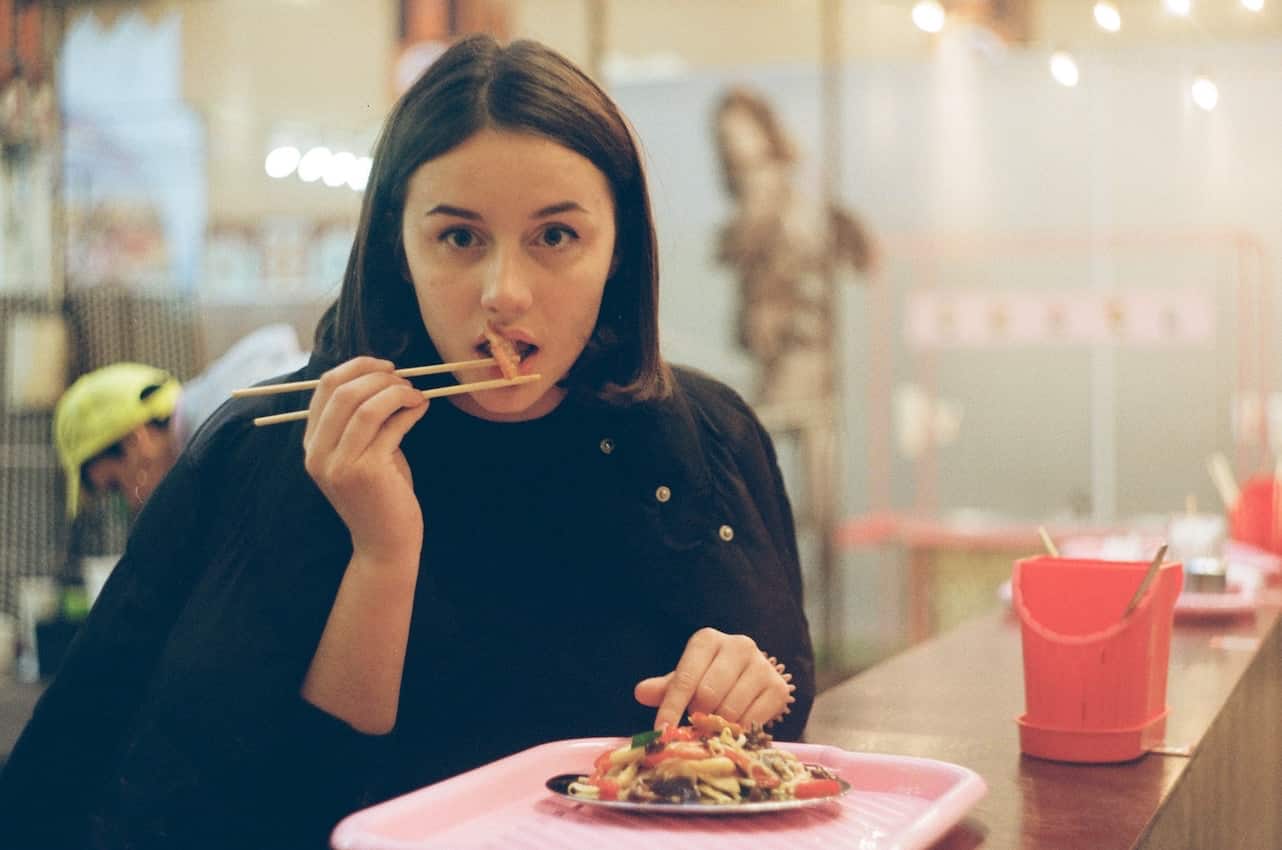 woman solo-eating asian food with chopsticks