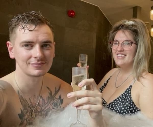 Two people enjoying champagne in a hot tub