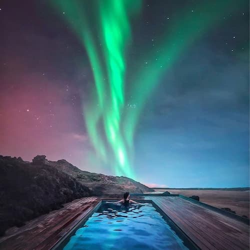 Woman swimming in a pool under the Northern Lights in Iceland