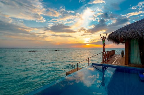 Woman in bungalow villa and infinity pool overlooking the Maldives