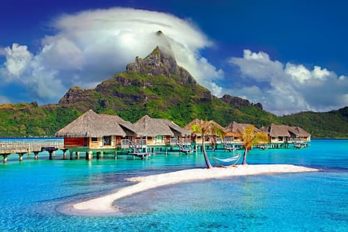 Bungalow villas over white sandy beach and blue waters of Bora Bora