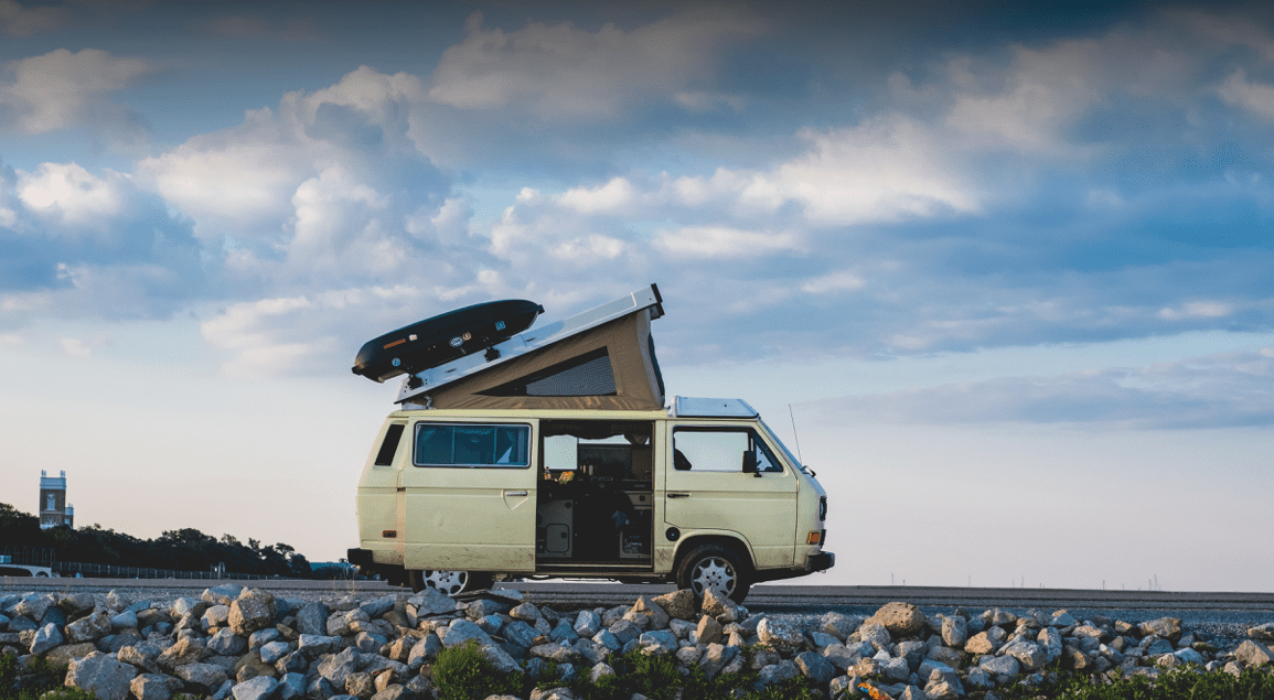 old VW camper van stopped on road with roof-bed opened up on top
